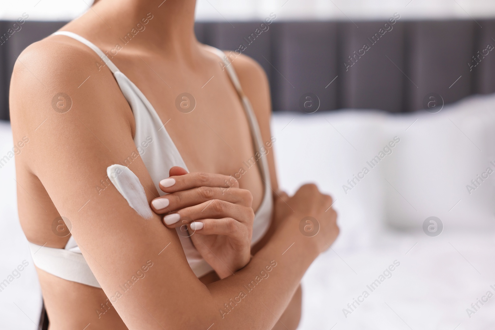 Photo of Body care. Woman applying cream onto arm indoors, closeup. Space for text