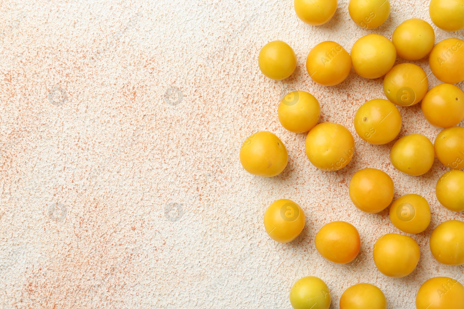 Photo of Tasty ripe plums on beige textured table, flat lay. Space for text