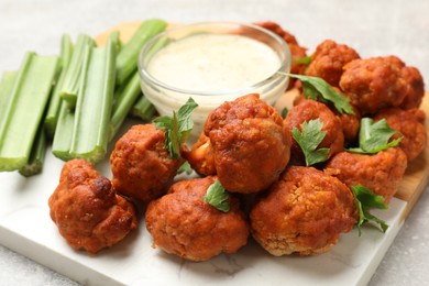 Photo of Baked cauliflower buffalo wings with celery and sauce on grey table, closeup