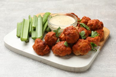 Photo of Baked cauliflower buffalo wings with celery and sauce on grey textured table, closeup