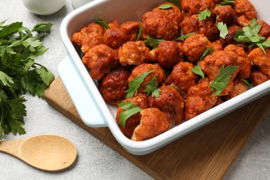 Photo of Baked cauliflower buffalo wings with parsley in baking dish on grey table