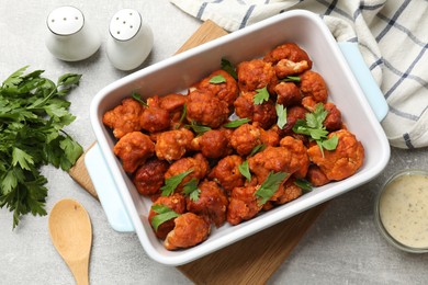 Photo of Baked cauliflower buffalo wings with parsley served on grey textured table, flat lay