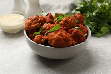 Photo of Baked cauliflower buffalo wings with parsley served on grey textured table, closeup