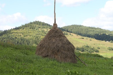 Photo of Pile of hay on field in mountains