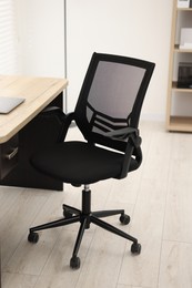 Black chair, laptop and desk in office