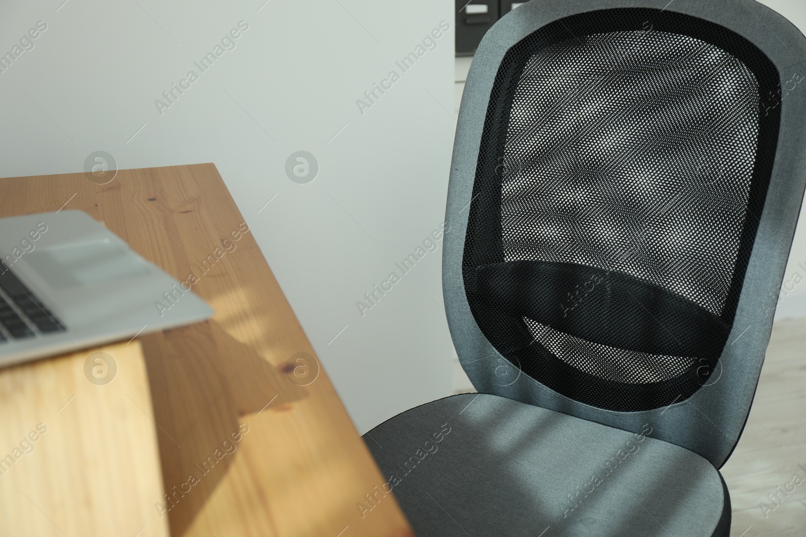 Photo of Grey chair, laptop and desk in office, closeup