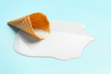 Photo of Melted ice cream and wafer cone on light background