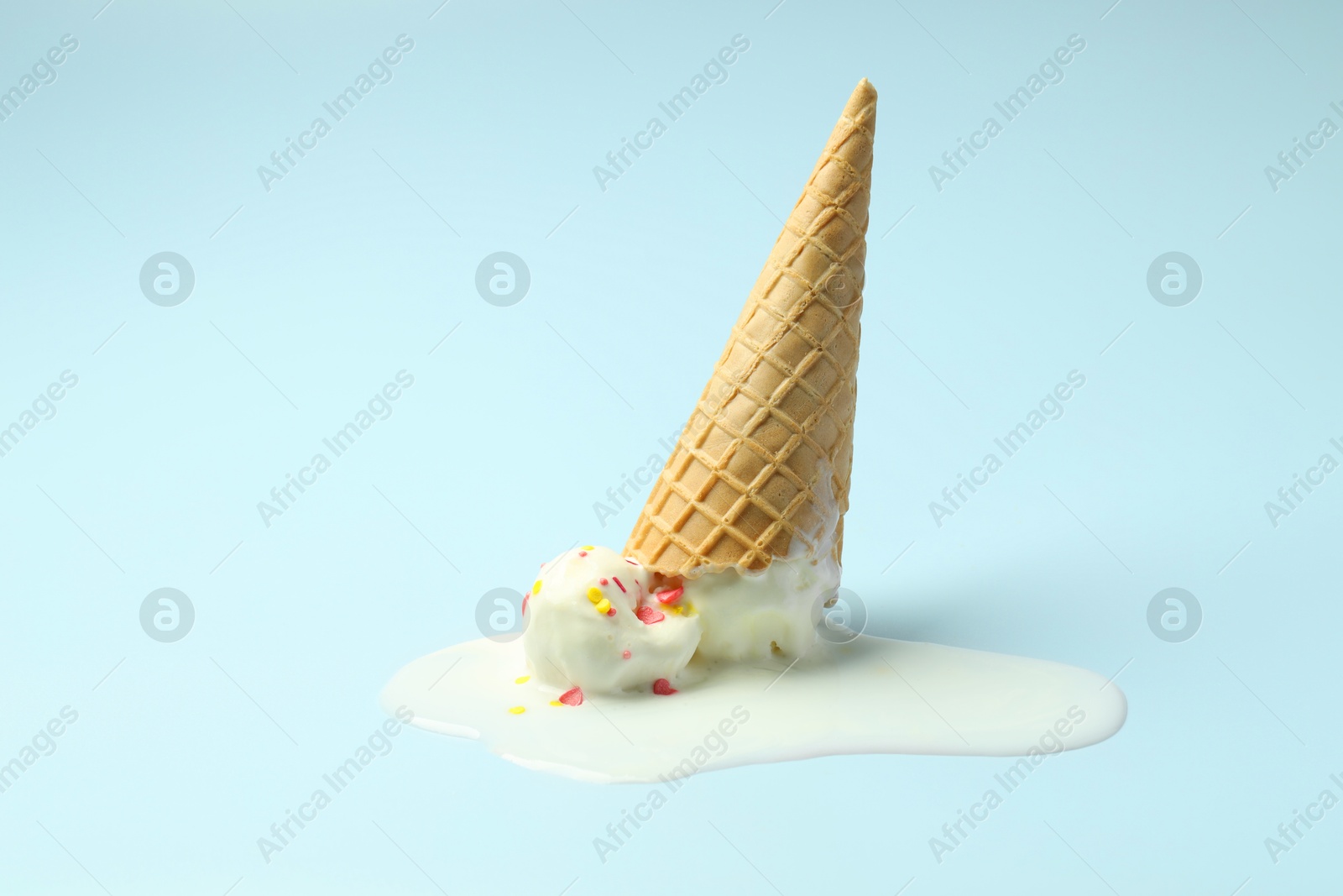 Photo of Melted ice cream in wafer cone on light background