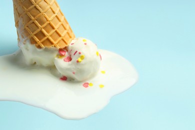 Photo of Melted ice cream in wafer cone on light background, closeup. Space for text