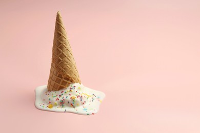 Photo of Melted ice cream in wafer cone on light pink background. Space for text