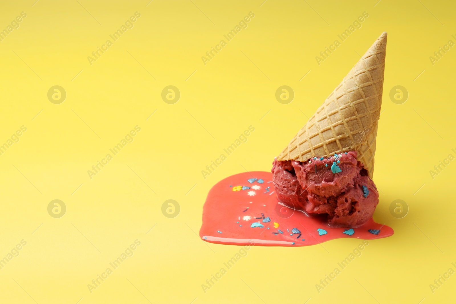 Photo of Melted ice cream in wafer cone on yellow background. Space for text