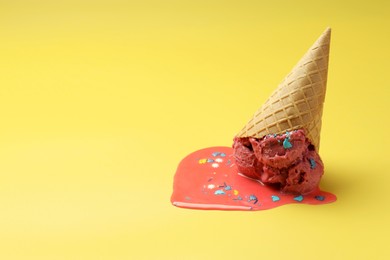 Melted ice cream in wafer cone on yellow background. Space for text