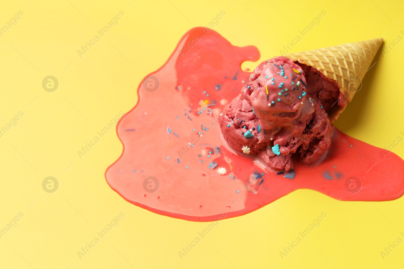 Photo of Melted ice cream in wafer cone on yellow background