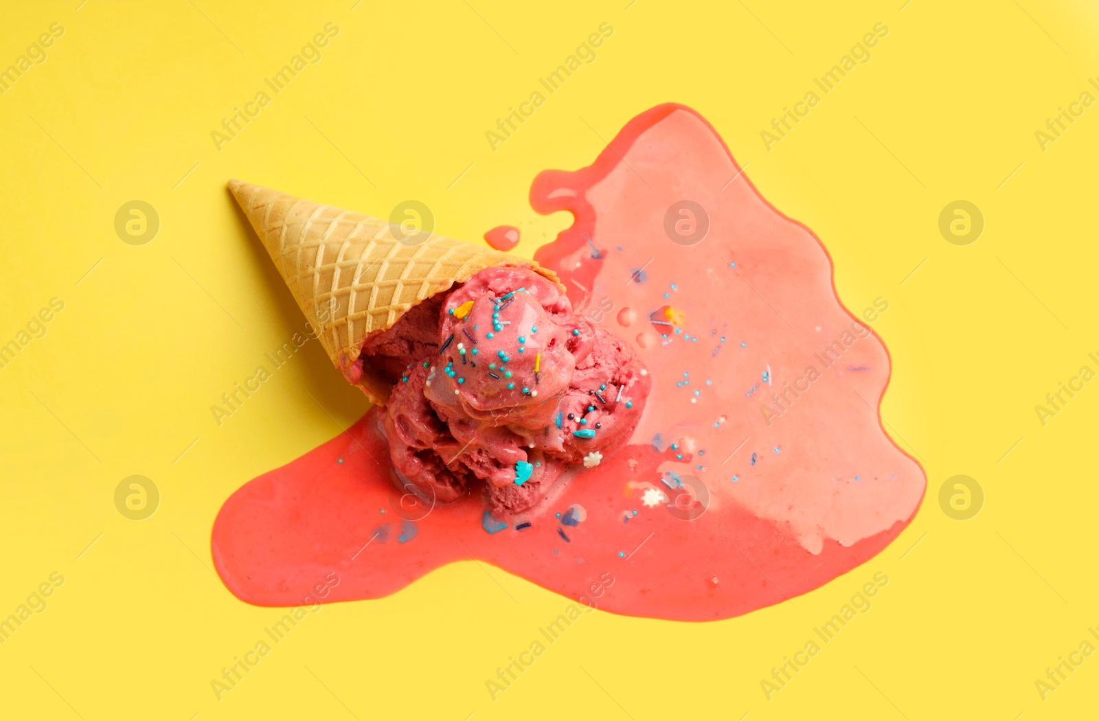 Photo of Melted ice cream in wafer cone on yellow background