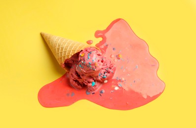 Melted ice cream in wafer cone on yellow background