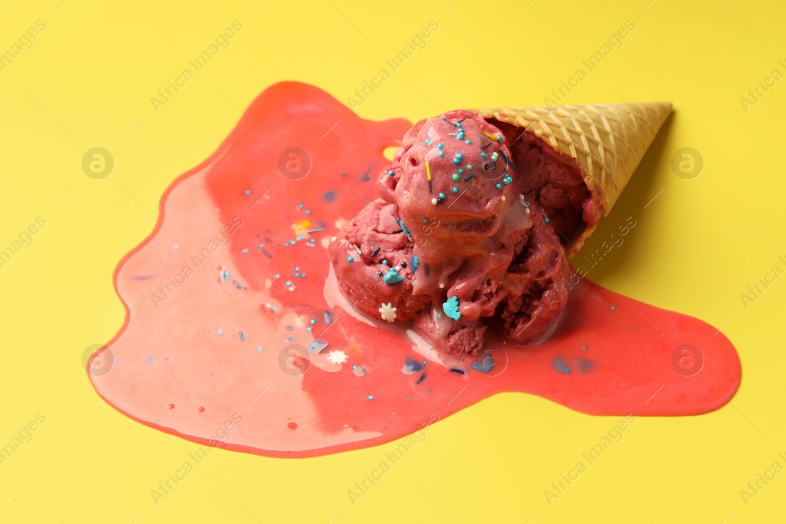 Photo of Melted ice cream in wafer cone on yellow background