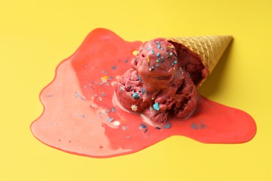 Melted ice cream in wafer cone on yellow background