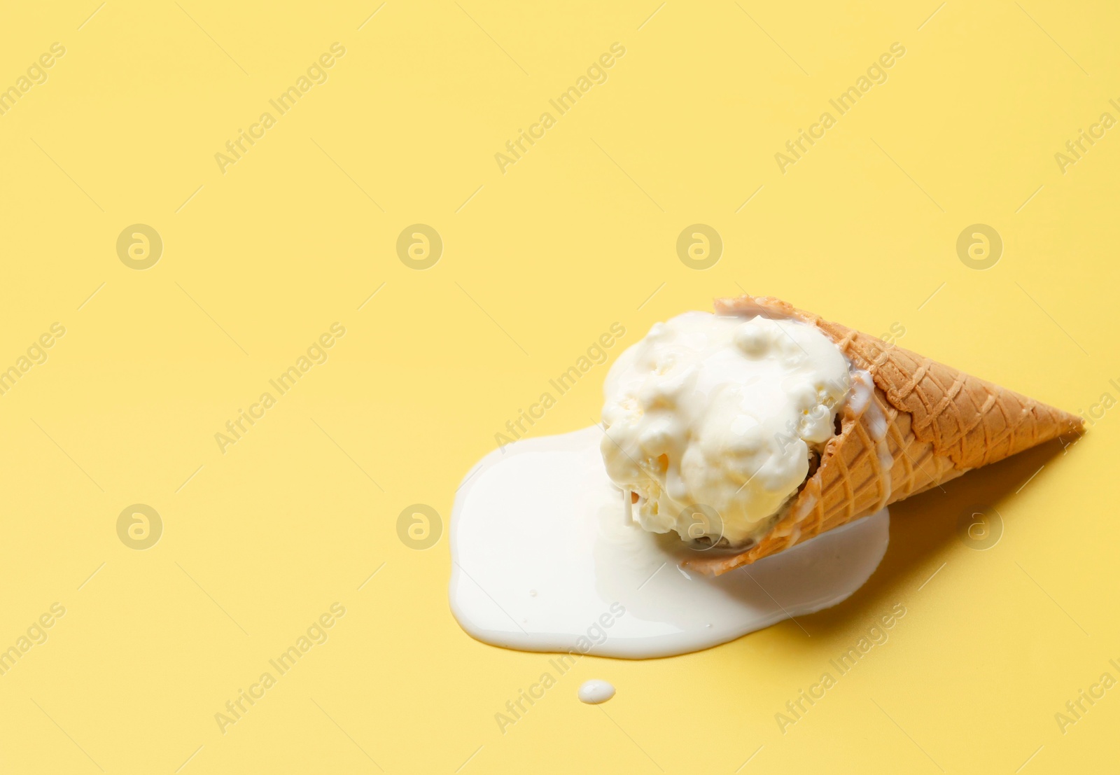 Photo of Melted ice cream in wafer cone on yellow background. Space for text