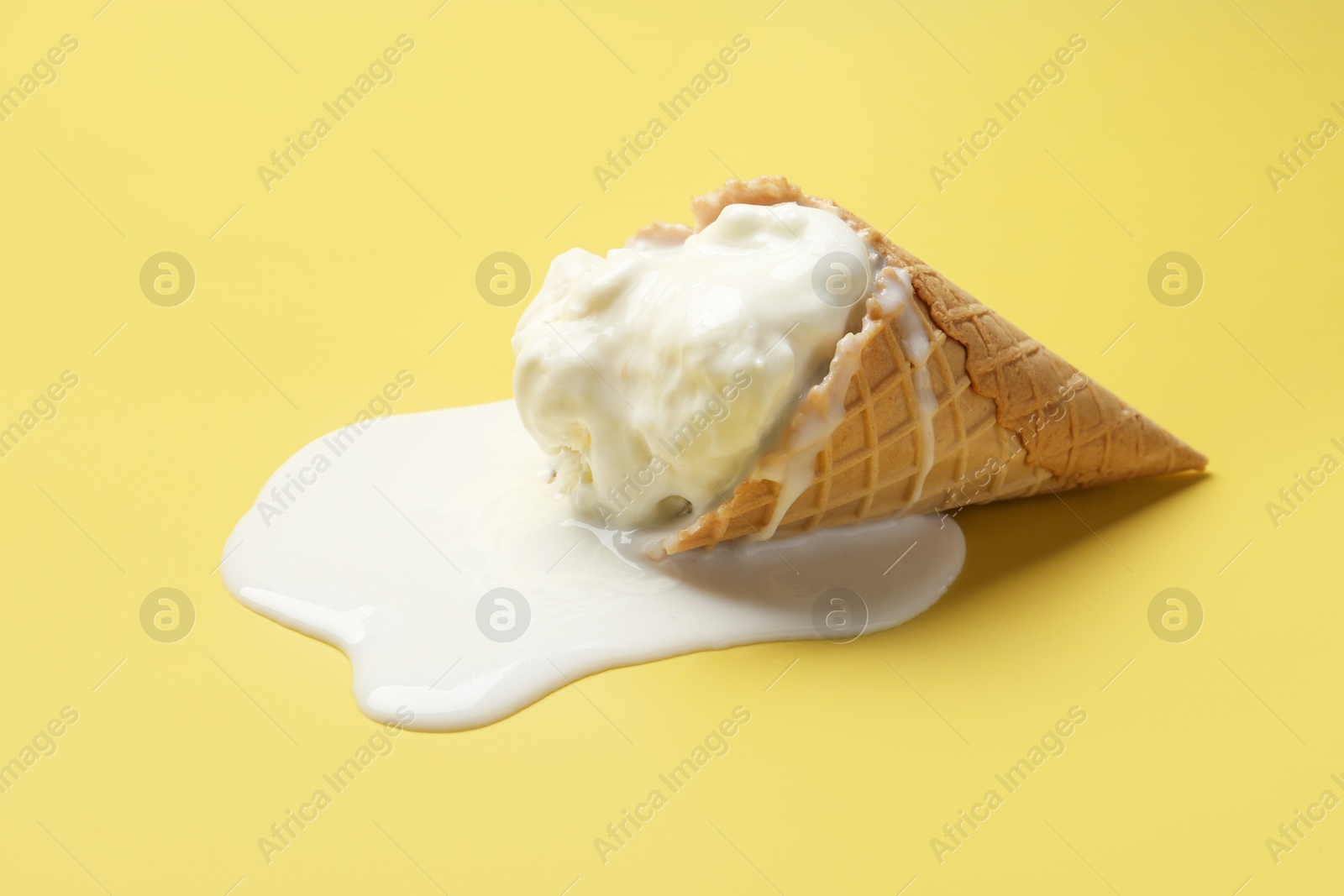 Photo of Melted ice cream in wafer cone on yellow background