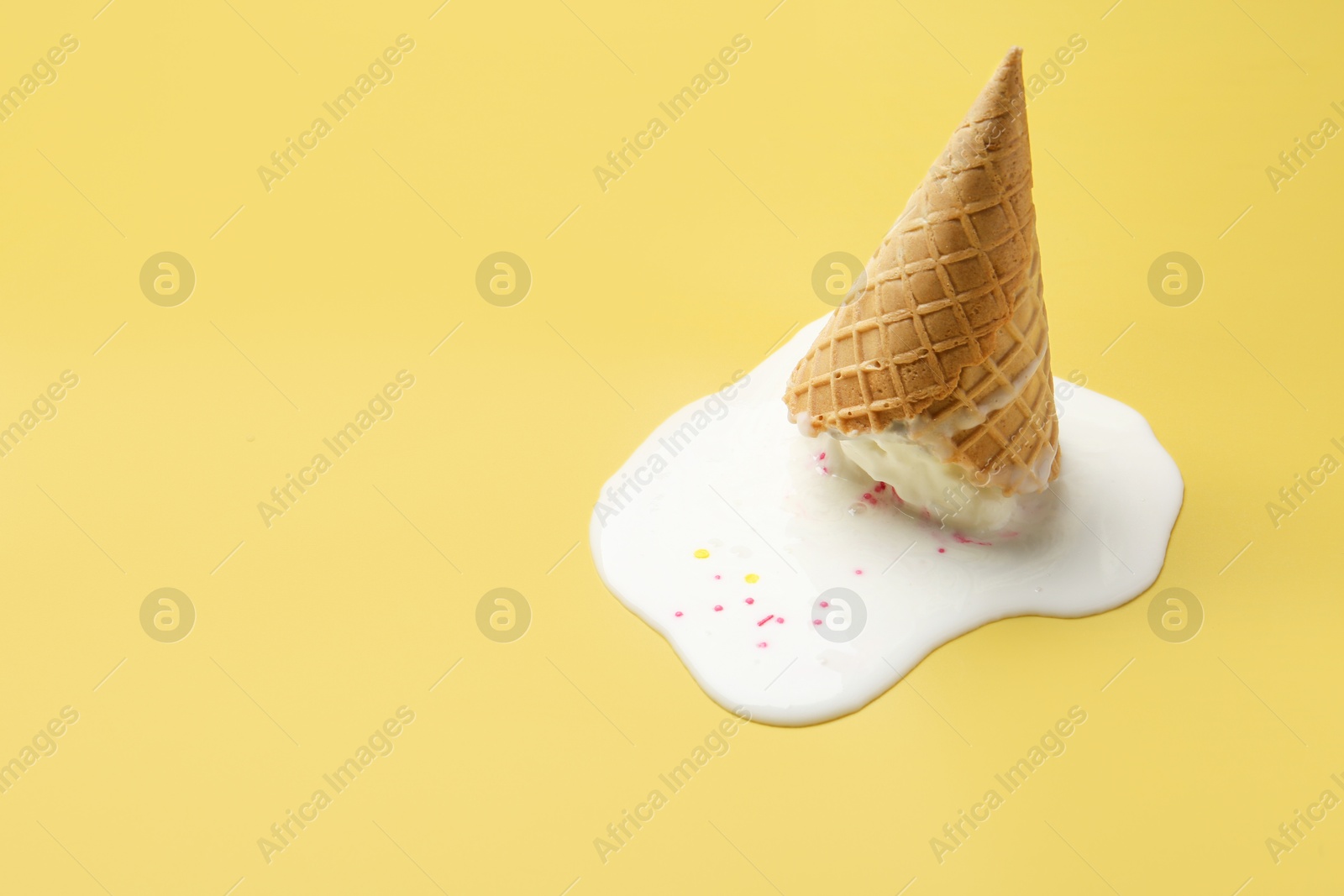 Photo of Melted ice cream in wafer cone on yellow background. Space for text