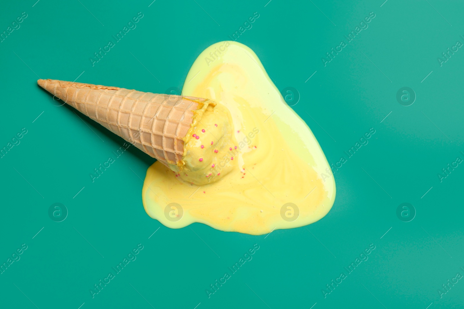 Photo of Melted ice cream in wafer cone on pale green background, top view. Space for text