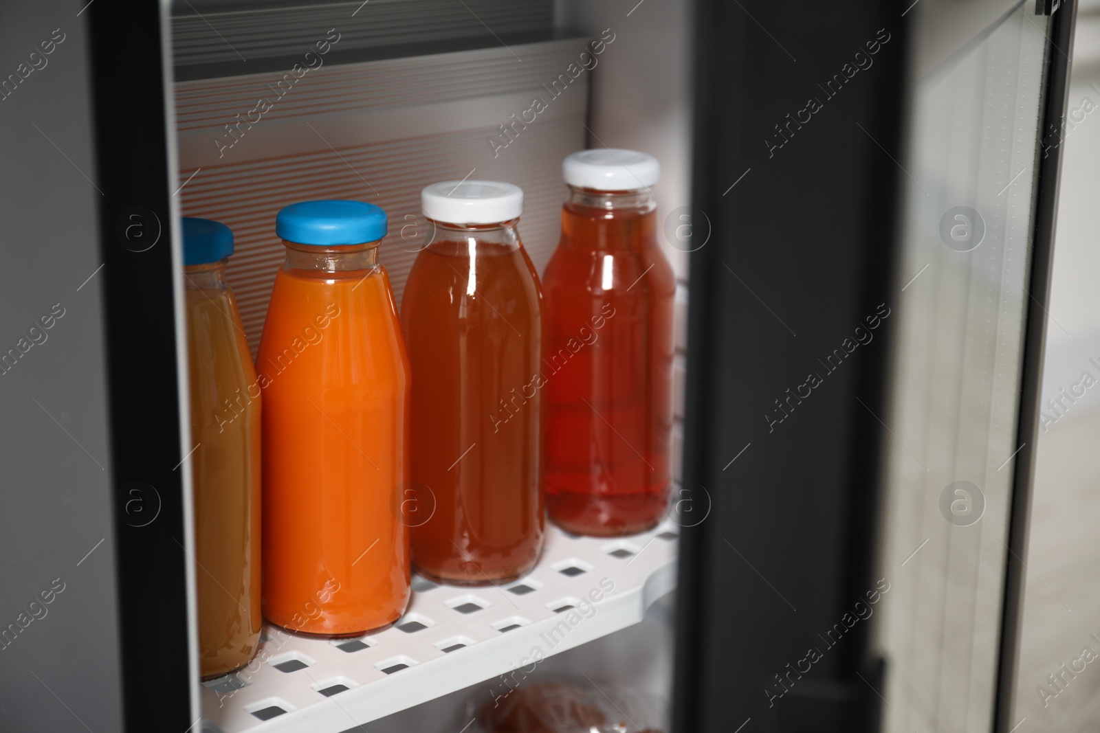 Photo of Open mini refrigerator with different drinks indoors