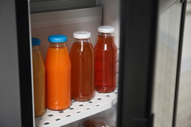 Photo of Open mini refrigerator with different drinks indoors