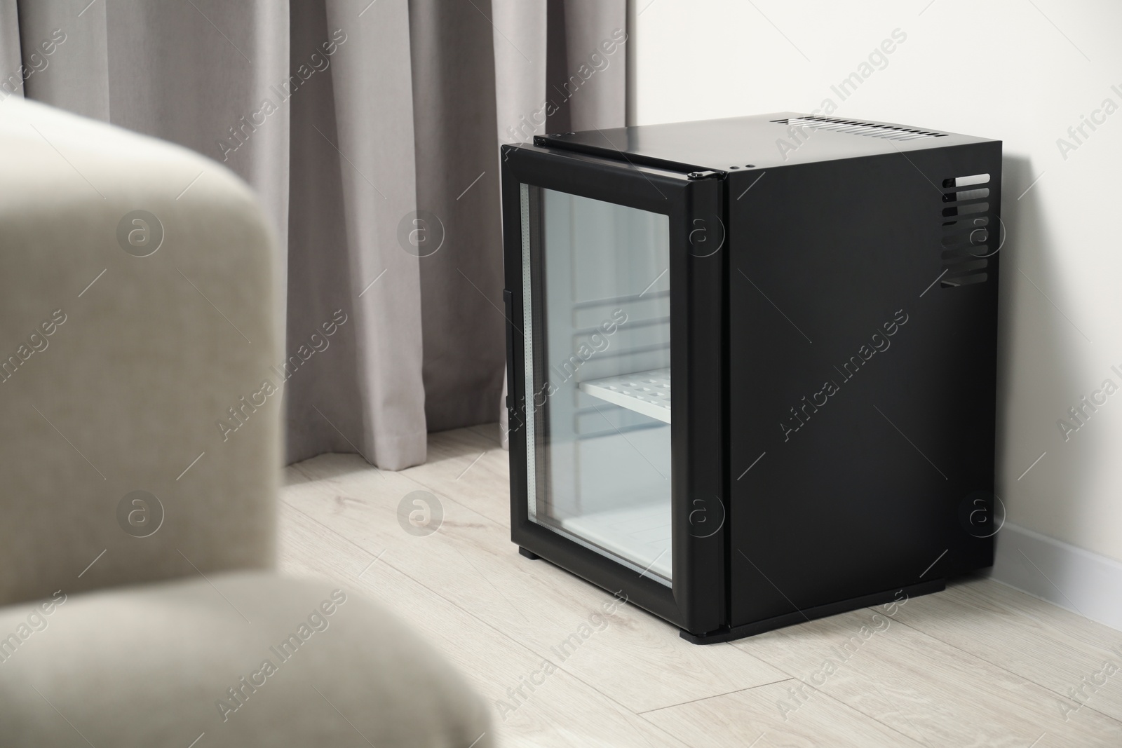 Photo of Empty modern mini refrigerator on floor indoors