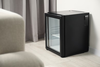 Empty modern mini refrigerator on floor indoors