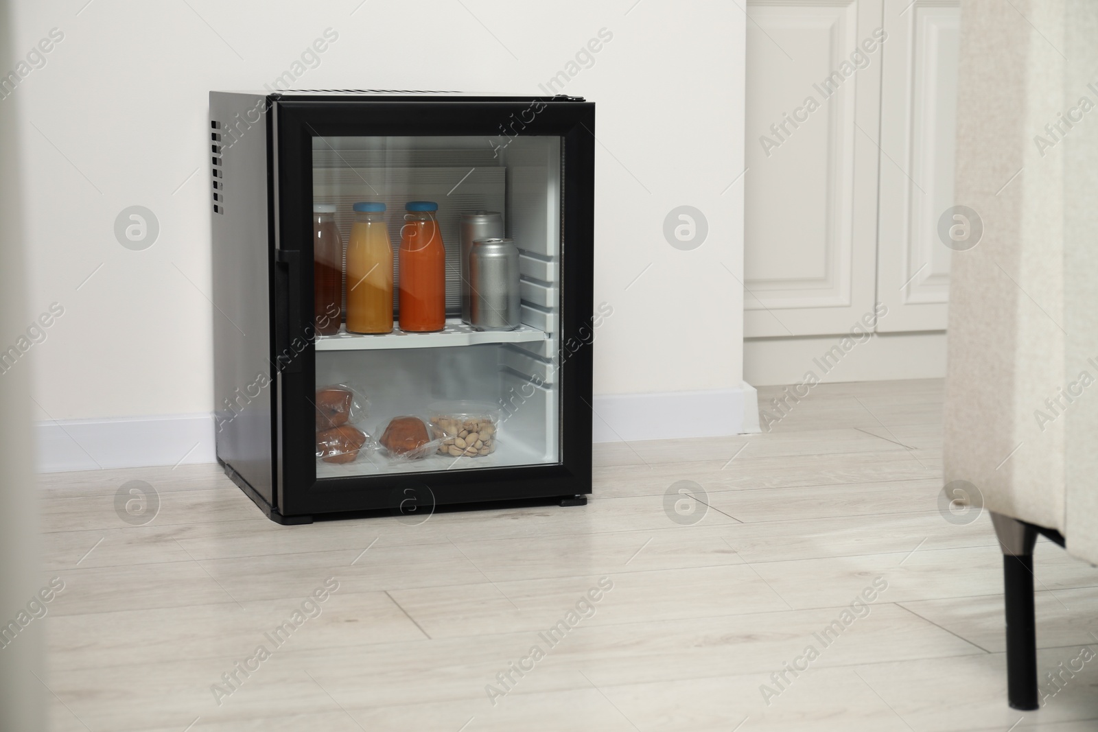 Photo of Mini refrigerator with different drinks and snacks indoors