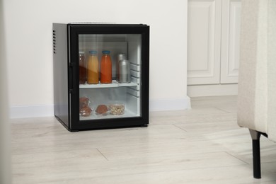 Mini refrigerator with different drinks and snacks indoors