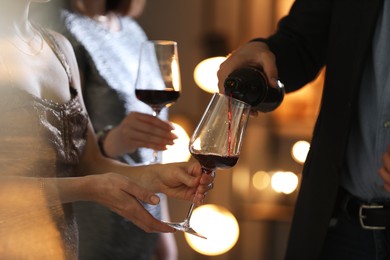 Photo of Man pouring wine into woman`s glass indoors, selective focus