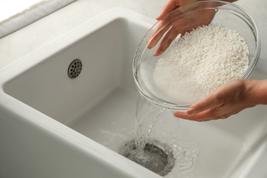 Woman rinsing rice in bowl above sink, closeup