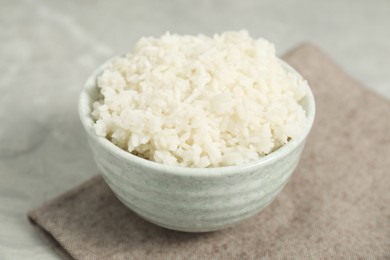 Photo of Delicious boiled rice in bowl on grey table, closeup