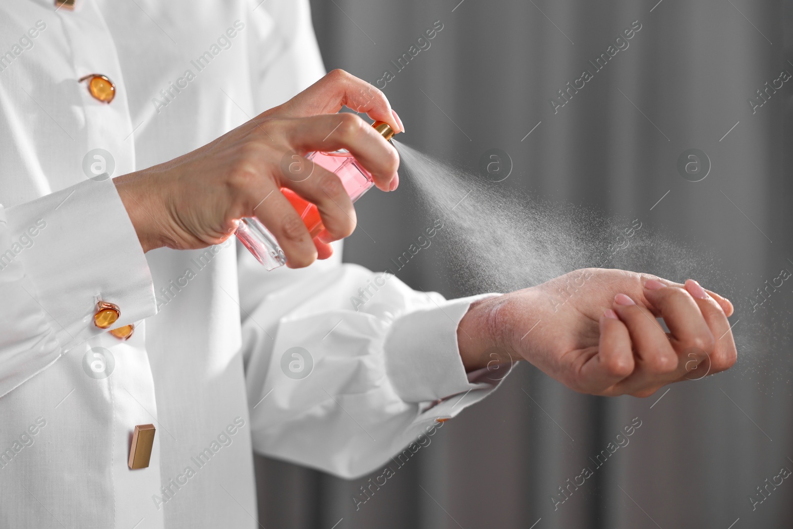 Photo of Woman spraying perfume onto wrist indoors, closeup