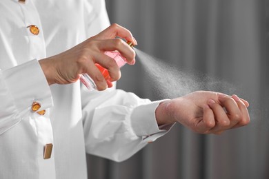 Photo of Woman spraying perfume onto wrist indoors, closeup