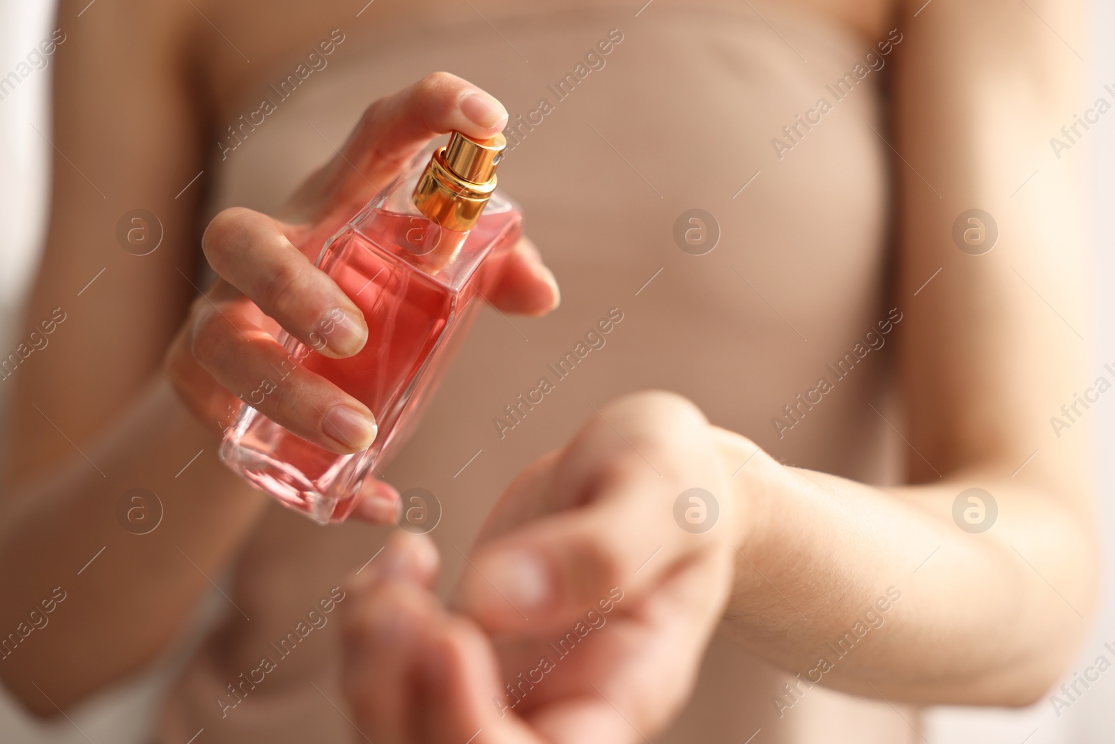 Photo of Woman spraying perfume onto wrist indoors, closeup