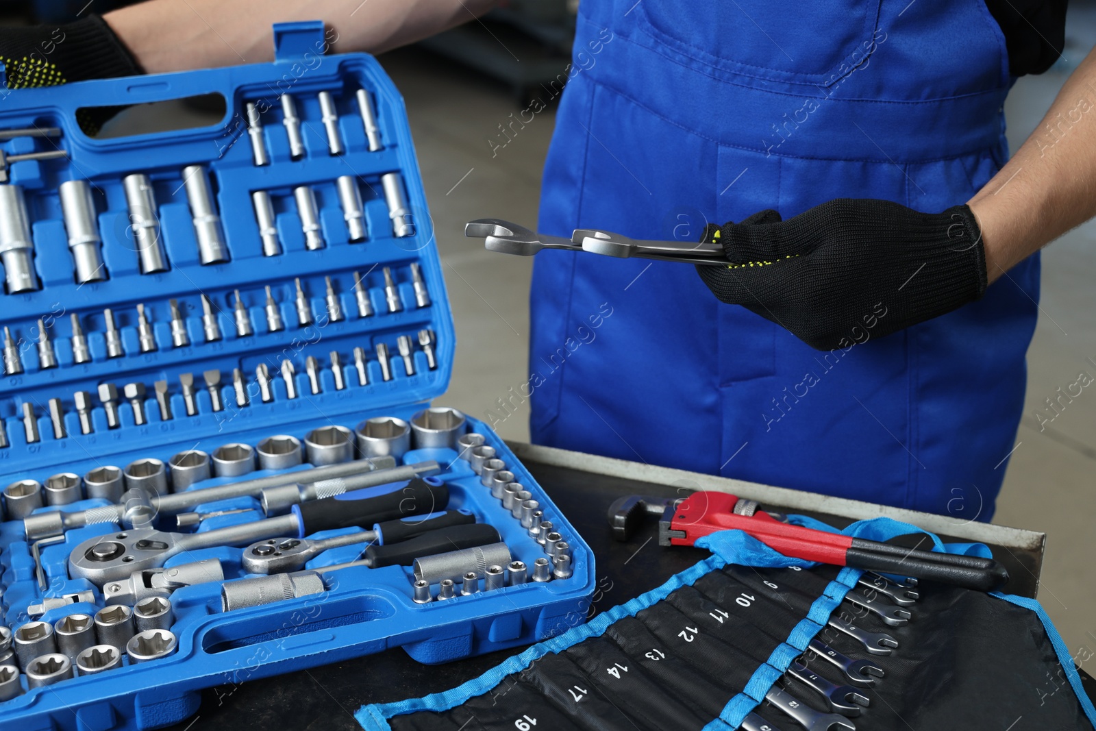 Photo of Auto mechanic with different tools at automobile repair shop, closeup