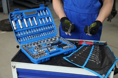 Photo of Auto mechanic with different tools at automobile repair shop, closeup