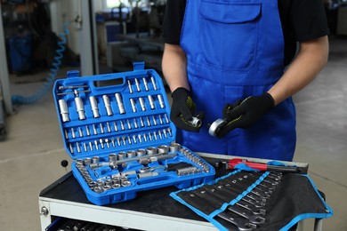 Photo of Auto mechanic with different tools at automobile repair shop, closeup