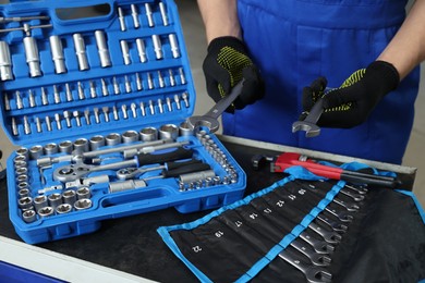 Photo of Auto mechanic with different tools at automobile repair shop, closeup