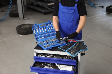 Photo of Auto mechanic with different tools at automobile repair shop, closeup