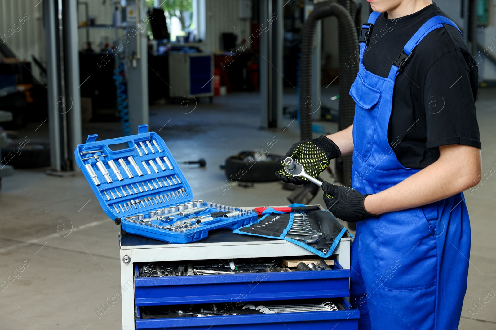 Photo of Auto mechanic with different tools at automobile repair shop, closeup