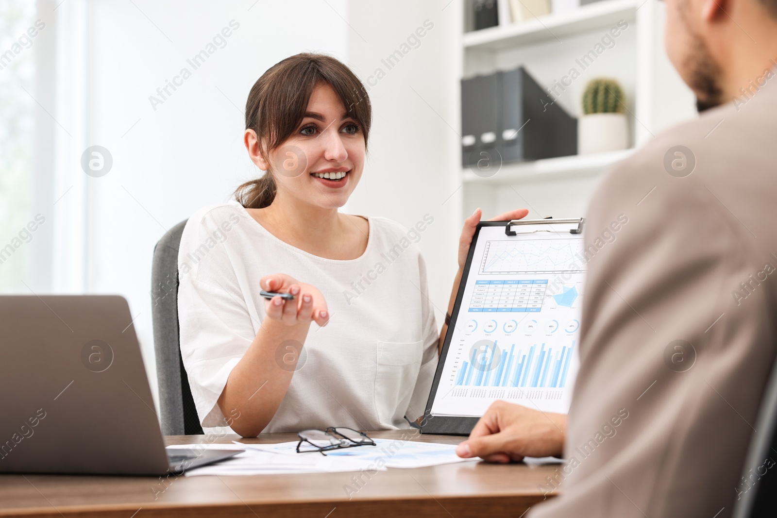 Photo of Smiling consultant working with client at table in office. Business meeting