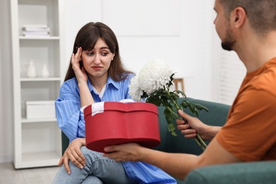 Photo of Embarrassed woman looking at man's gifts indoors