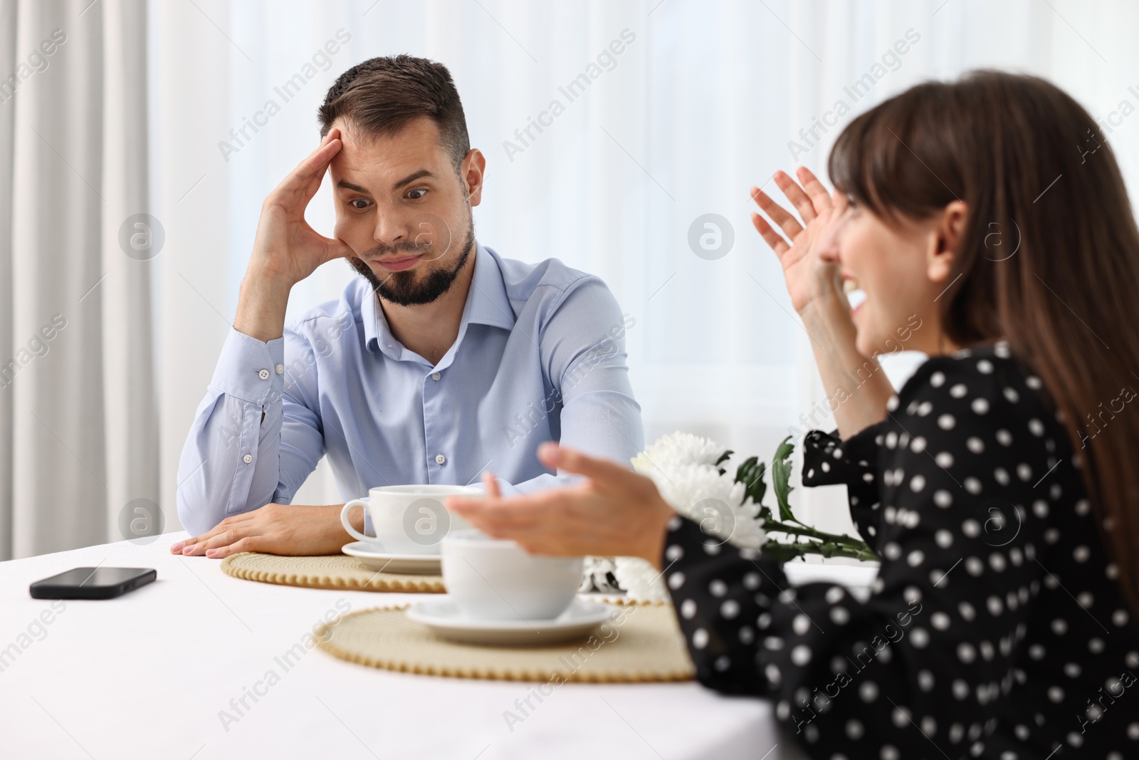 Photo of Embarrassing date. Obsessive woman talking to shocked man at table indoors