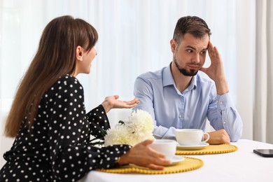 Embarrassing date. Obsessive woman talking to shocked man at table indoors