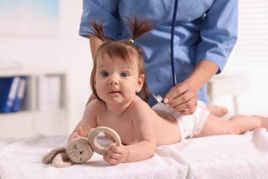 Pediatrician examining cute little girl with stethoscope in clinic, closeup. Checking baby's health