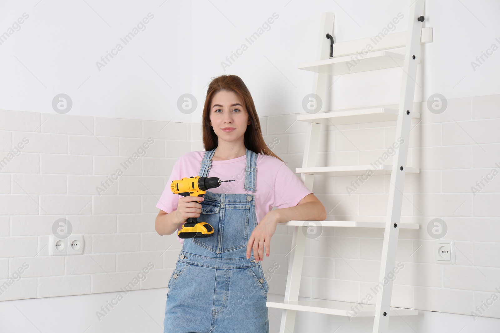 Photo of Woman with electric screwdriver indoors. Assembling furniture