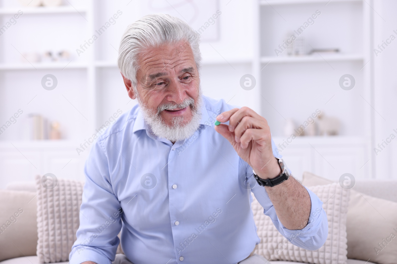 Photo of Senior man with pill on sofa at home